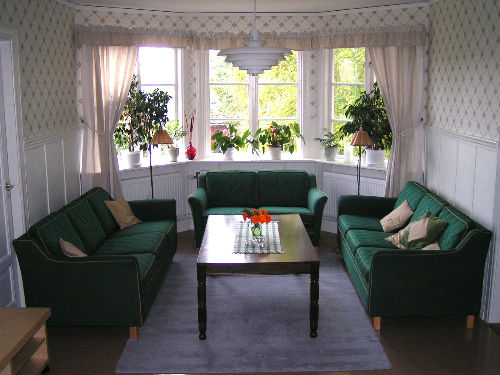 Ett rum med tre gröna soffor runt ett bord för konferens nära Stockholm & Uppsala